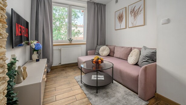 Ett modernt vardagsrum med en soffa, ett soffbord, en tv och ett fönster med gardiner.