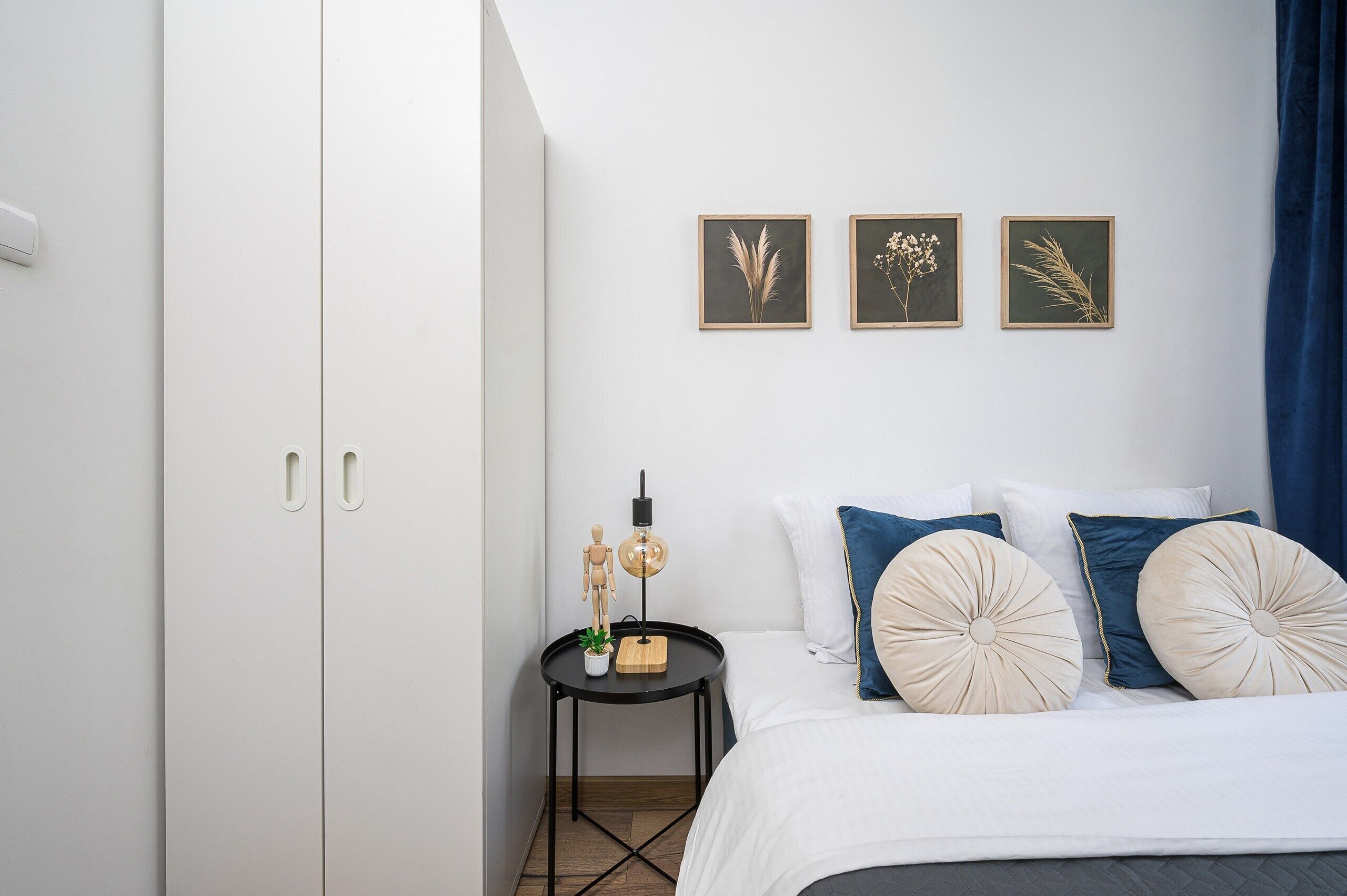 A bedroom with a bed, a nightstand, and three framed botanical prints on the wall.
