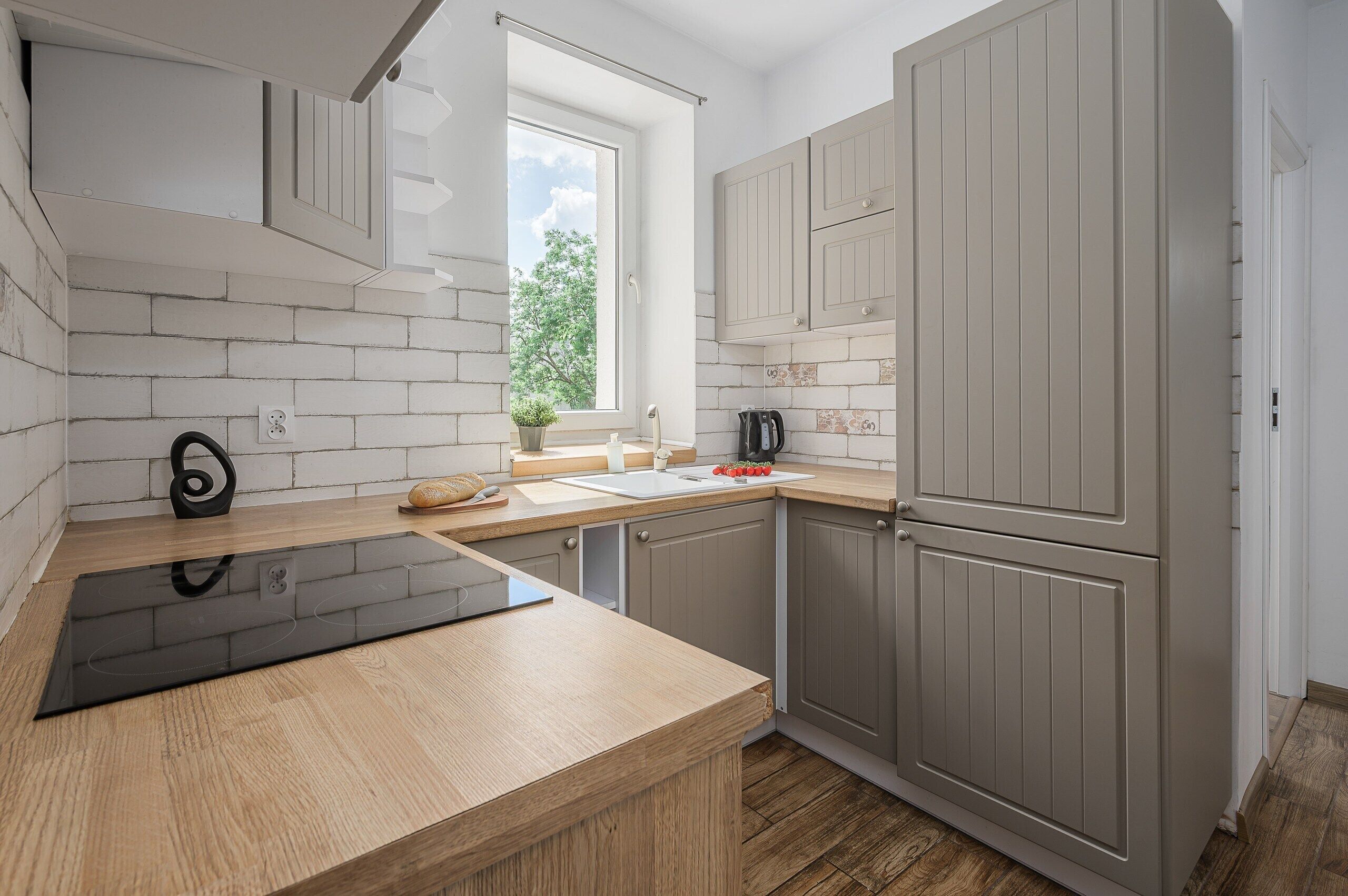 A modern kitchen with a wooden countertop, a built-in oven, and grey cabinets.