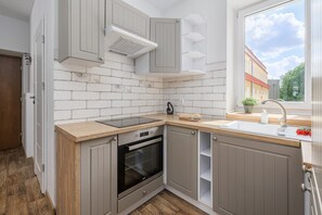 A kitchen with a built-in oven, a sink, and a window with a view of buildings. - Lumina Family 4-room Apart near Metro  (Warszawa)