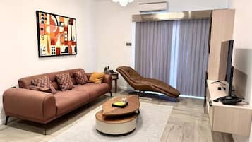 A modern living room with a sofa, a coffee table, a recliner, a desk, and a television.