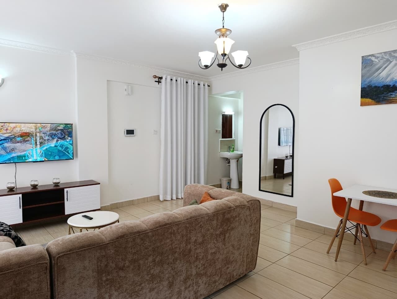 A modern living room with a sofa, TV, dining table, and chairs.