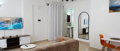 Una sala de estar moderna con sofá, televisión y comedor.