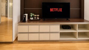 Ein modernes Wohnzimmer mit einem an der Wand befestigten Flachbildfernseher, einem darunterliegenden Einbauschrank und einer Tür zu einem anderen Raum.