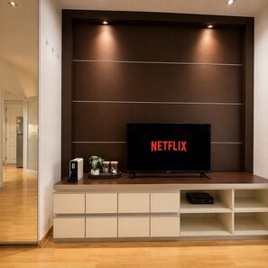 Ein modernes Wohnzimmer mit einem an der Wand befestigten Flachbildfernseher, einem darunterliegenden Einbauschrank und einer Tür zu einem anderen Raum.