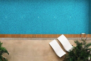 En swimmingpool med en kant av kakel, två vita handdukar och en metallstege.