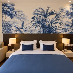 A hotel room with a large bed, two bedside lamps, a headboard with a floral mural, and a nightstand with a lamp. - One quiet bedroom apartment with amazing balcony views next to Nana and Soi 11 (Khet Khlong Toei)