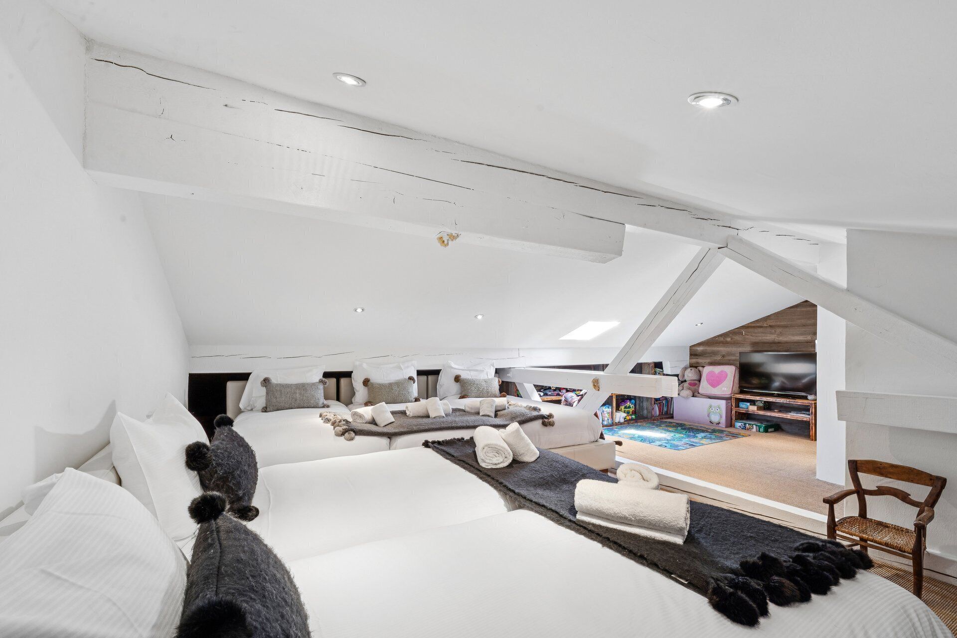 Une chambre spacieuse de style loft, avec un plafond en pente, un grand lit, un coin salon et un téléviseur.