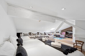 Ein geräumiges Schlafzimmer im Loft-Stil mit schrägen Wänden, einem großen Bett, einer Sitzecke und einem Fernseher.