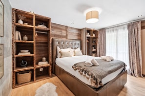 Ein geräumiges Schlafzimmer mit einem großen Bett, Holzregalen und einem Kleiderschrank.