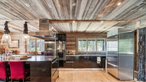 A modern kitchen with wooden ceiling beams, stainless steel appliances, and a large window. - The Crest by Mrs Miggins ****Welcome to The Crest by Mrs Miggins ****, an exceptional chalet nestled (Crans-Montana)