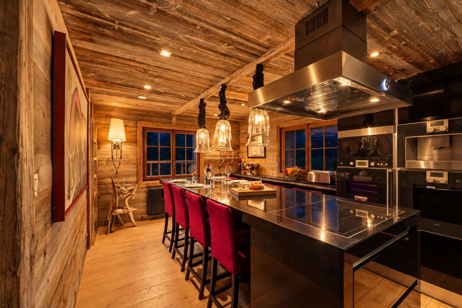 A kitchen with wooden walls, a bar area with red chairs, and modern stainless steel appliances.