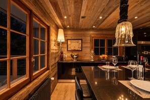 Ein Holzinterieur mit Barbereich, einem für zwei Personen gedeckten Esstisch und einem großen Fenster.