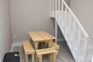 Un escalier avec des rampes blanches et une table en bois avec des bancs, dans une pièce aux murs de couleur claire.