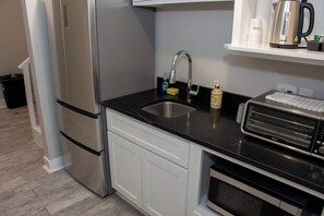 A modern kitchen with a stainless steel refrigerator, a sink, a toaster, and a coffee maker on the countertop.