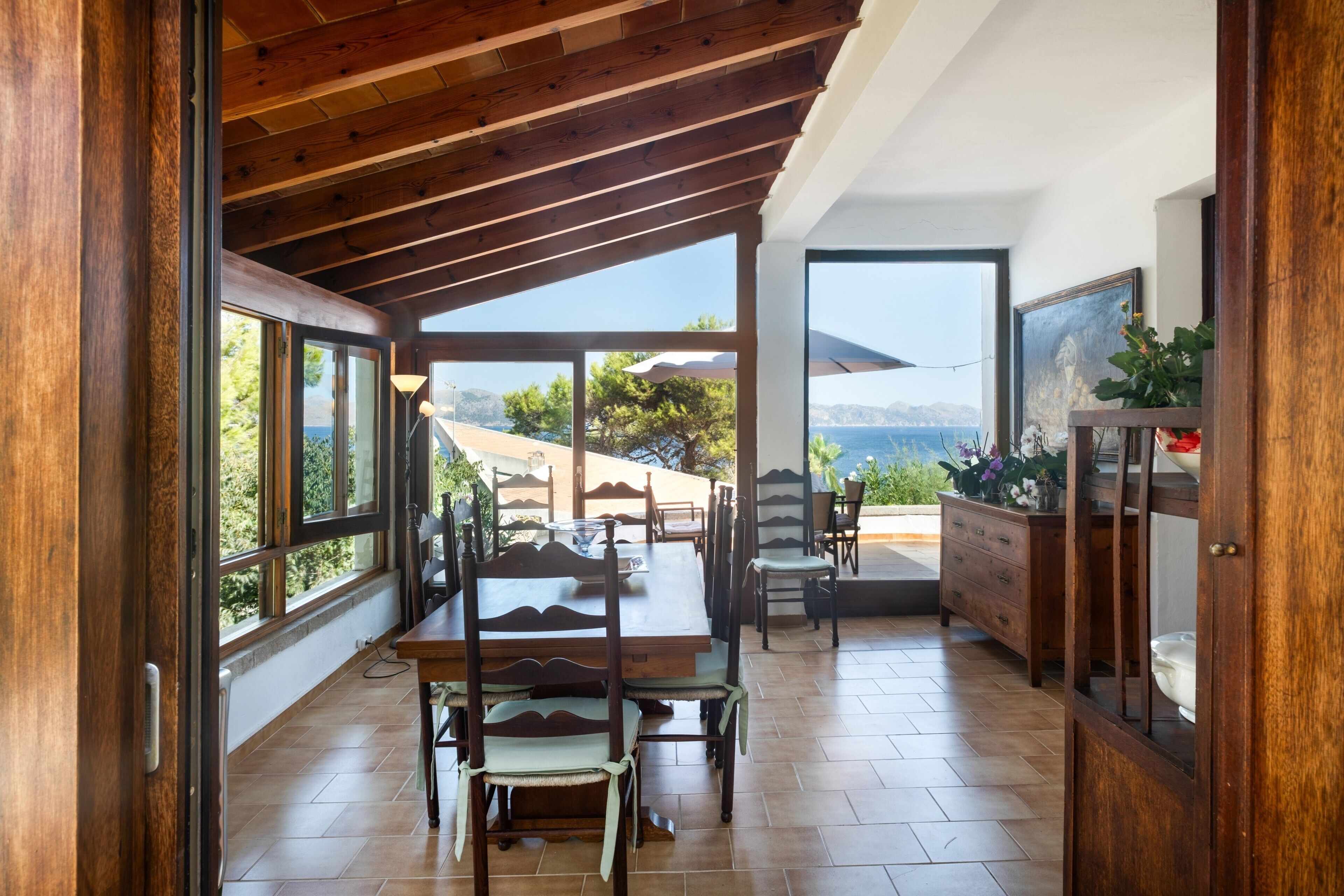 Una camera spaziosa con soffitto in legno, ampie finestre e vista sul mare.