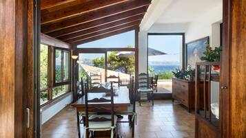 Una camera spaziosa con soffitto in legno, ampie finestre e vista sul mare.