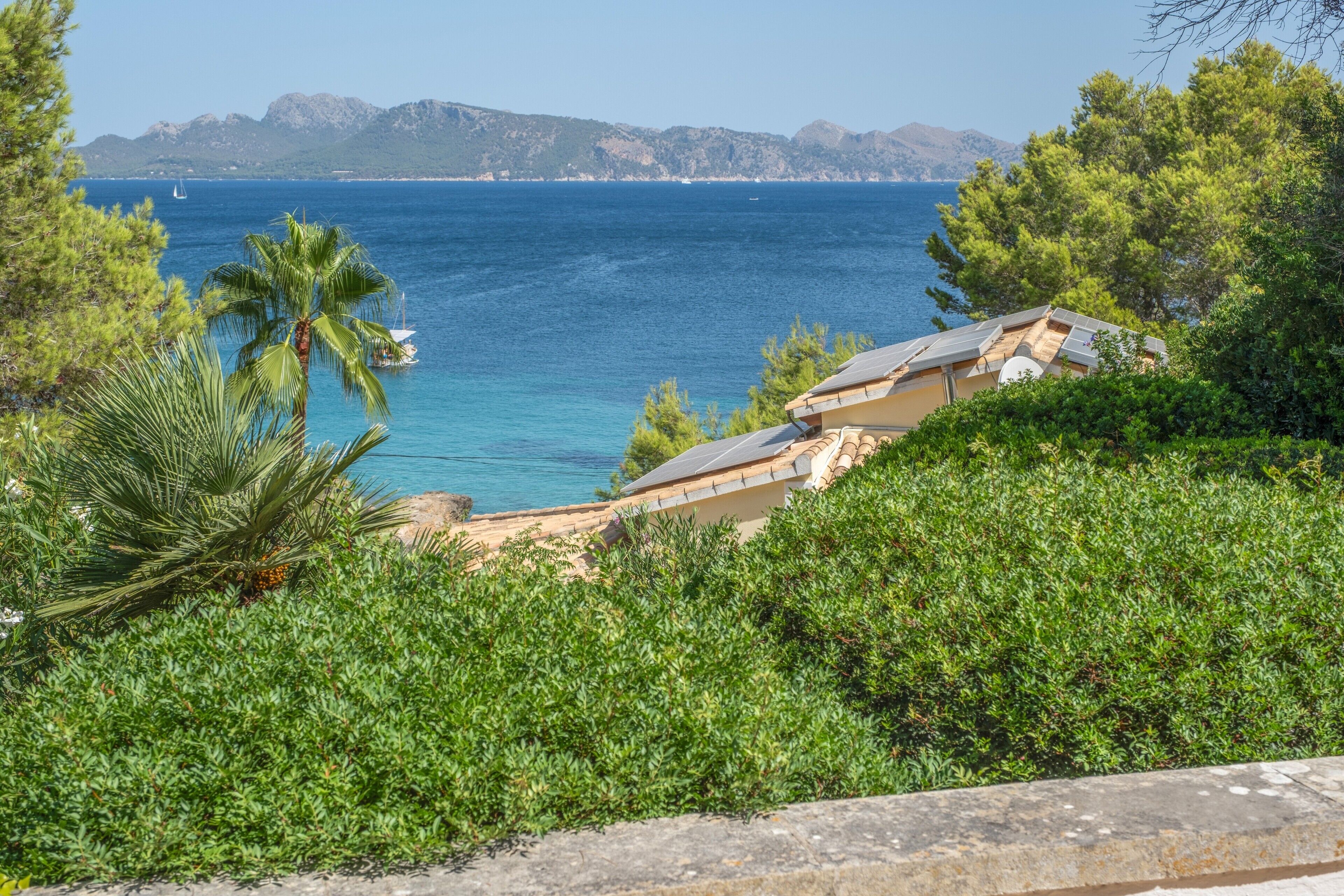 Una proprietà costiera con vista sul mare, immersa nel verde e con montagne sullo sfondo.
