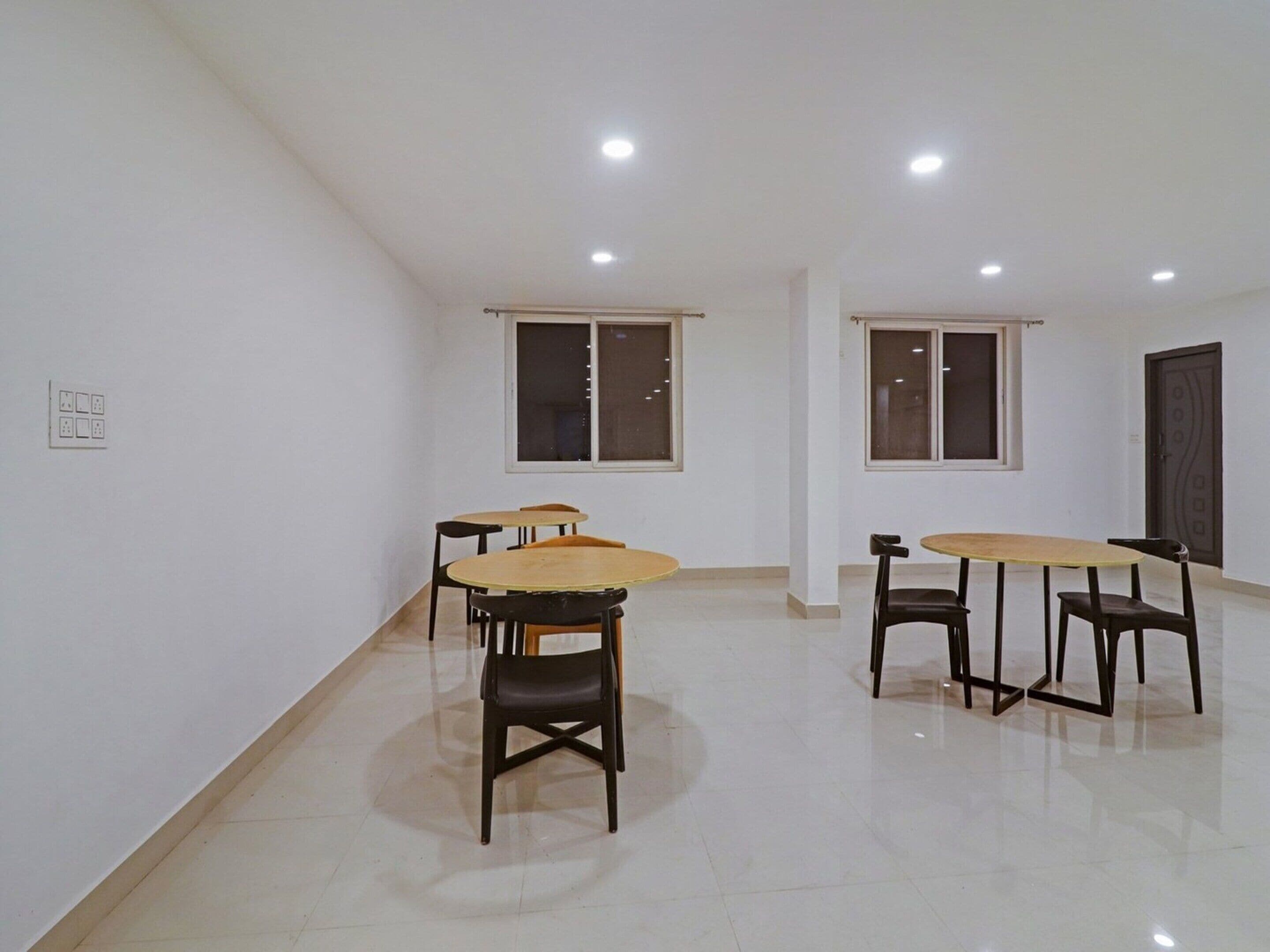 A room with two tables and four chairs, a door, and two windows.