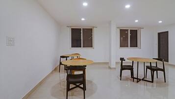 A room with two tables and four chairs, a door, and two windows.