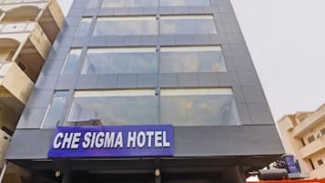 A modern hotel building with a prominent sign for 'CHE SIGMA HOTEL' on the facade.
