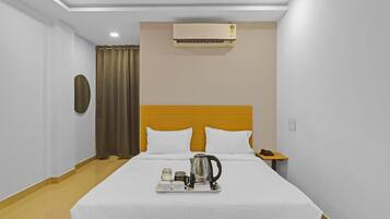 A hotel room with a bed, a nightstand, a telephone, an air conditioning unit, and a ceiling fan.
