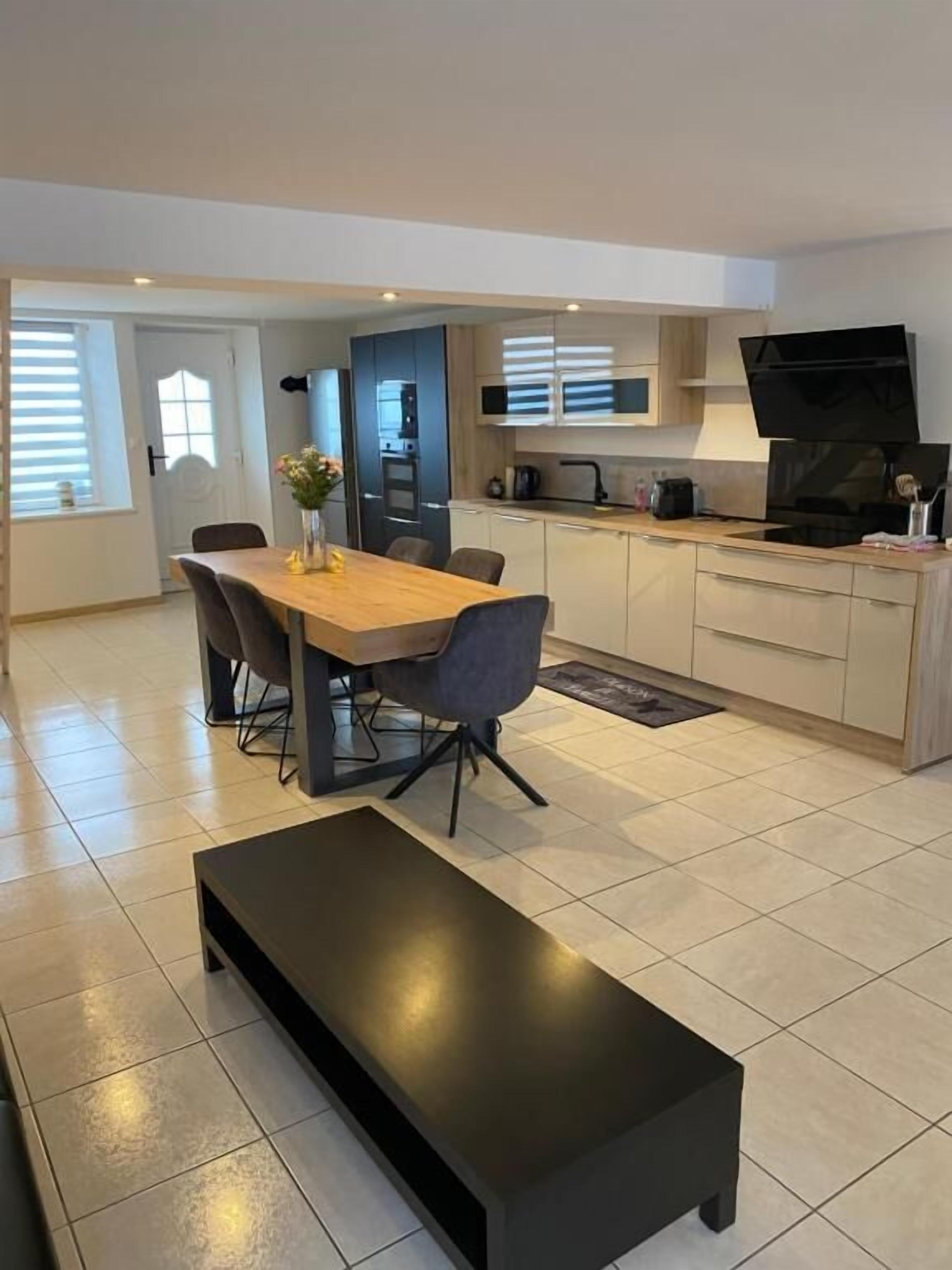 Una cocina moderna con comedor, un banco negro y un televisor.