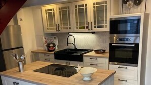 Una cocina moderna con armarios blancos, una isla central, electrodomésticos de acero inoxidable y encimera de madera.