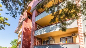 A multi-story building with balconies, a car parked in front, and trees in the background. - Apis Deluxe Double Room - Kalydon Suite (Benevento)