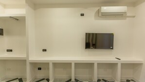A room with a mounted air conditioner, a flat-screen TV, and a tiled floor. - Apis Deluxe Double Room - Kalydon Suite (Benevento)