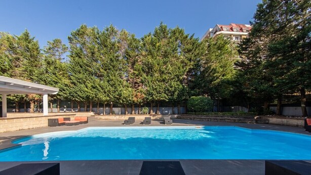 A swimming pool with lounge chairs, surrounded by trees and a building in the background. - Apis Deluxe Double Room - Kalydon Suite (Benevento)