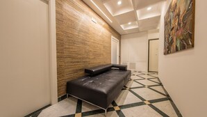 A hallway with a black leather bench, a patterned floor, and a wooden wall. - Apis Deluxe Double Room - Kalydon Suite (Benevento)