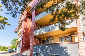A multi-story building with balconies, a car parked in front, and trees in the background. - Sofia Room - Deluxe Double Room - Kalydon Suite (Benevento)