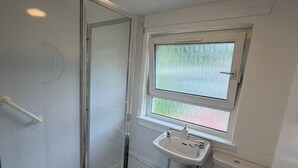 A bathroom with a glass shower enclosure, a sink, and a toilet. - The Narrows - Macaulay Letting (Rhu)