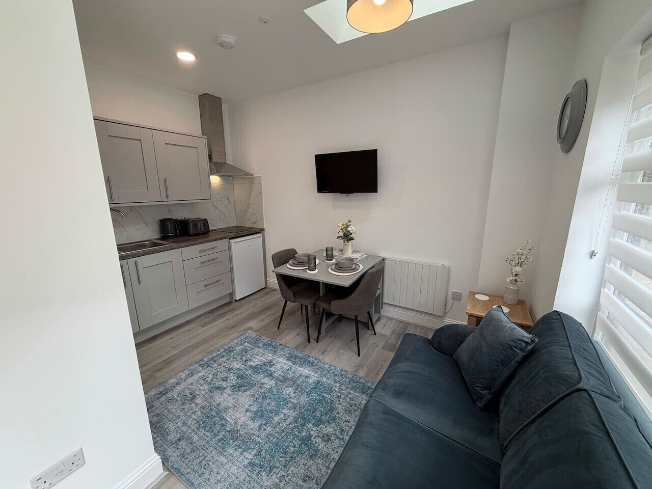 A compact living space with a kitchenette, a dining area, and a seating area with a sofa.