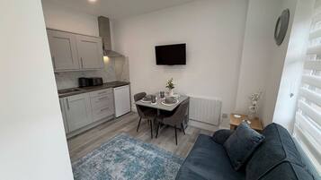 A compact living space with a kitchenette, a dining area, and a seating area with a sofa.