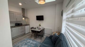 A compact living space with a kitchenette, a dining area, and a seating area with a sofa.