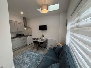 A compact living space with a kitchenette, a dining area, and a seating area with a sofa. - The Annexe - Macaulay Letting (Argyll and Bute Council)
