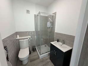 Ein Badezimmer mit Toilette, einer Duschkabine und einem Waschbecken.