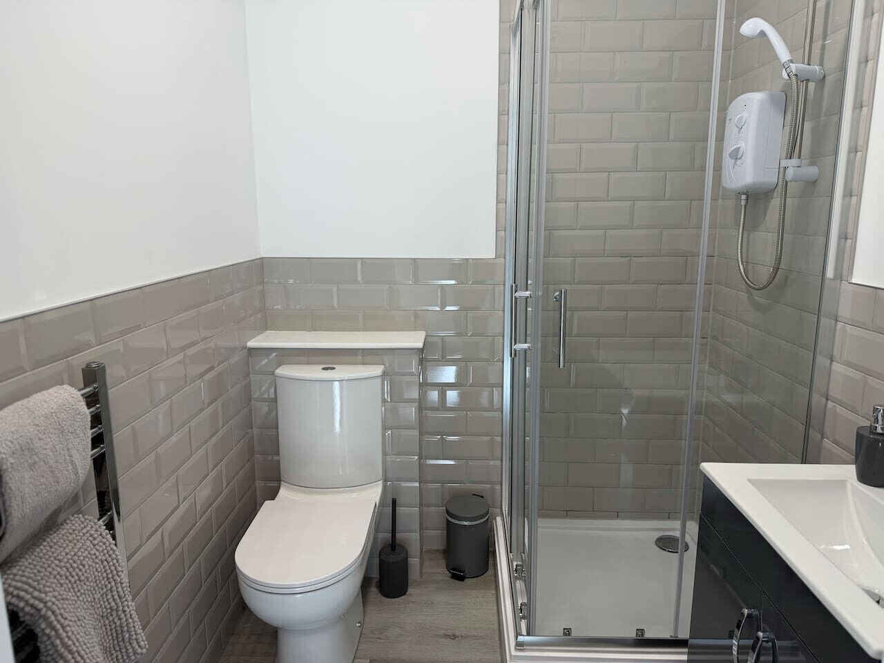 A bathroom with a toilet, a shower enclosure, and a sink.