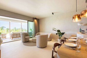 Ein modernes Wohnzimmer mit Essbereich, großen Fenstern und Blick ins Freie.