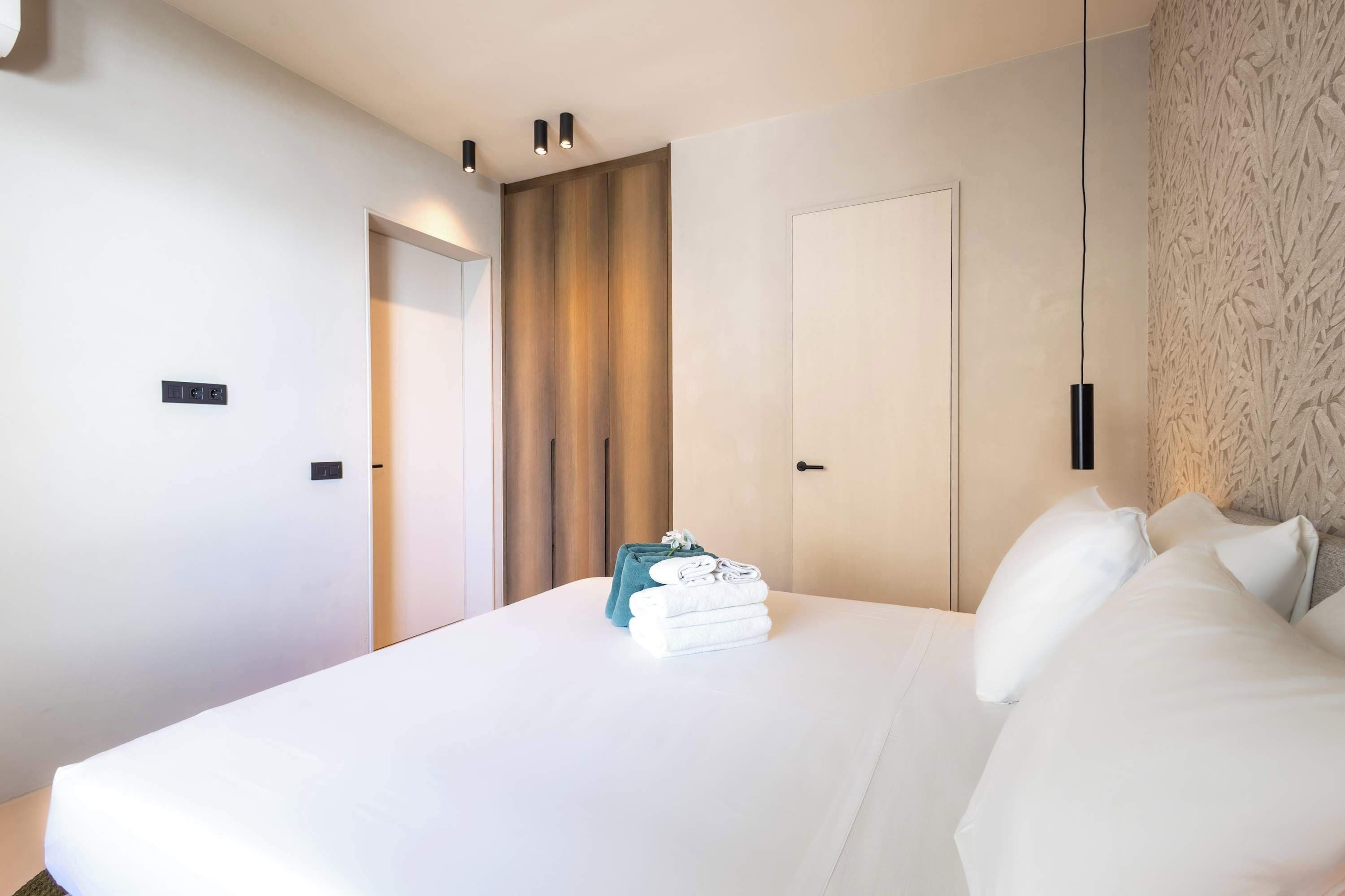 Ein Hotelzimmer mit einem großen Bett, einem Kleiderschrank, einer Tür und einer Wandleuchte.