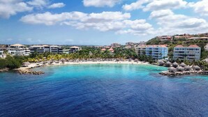 A coastal resort with a beachfront, palm trees, and multiple hotel buildings. - Private Pool Escape - Luminara at The Reef (Sint Michiel)