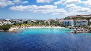 Ein Küstenresort mit Strand, Palmen und mehreren Hotelgebäuden.