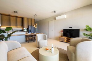 Ein modernes Wohnzimmer mit einem Flachbildfernseher, einem Essbereich mit einem Holztisch und einer Küche mit Holzschränken.