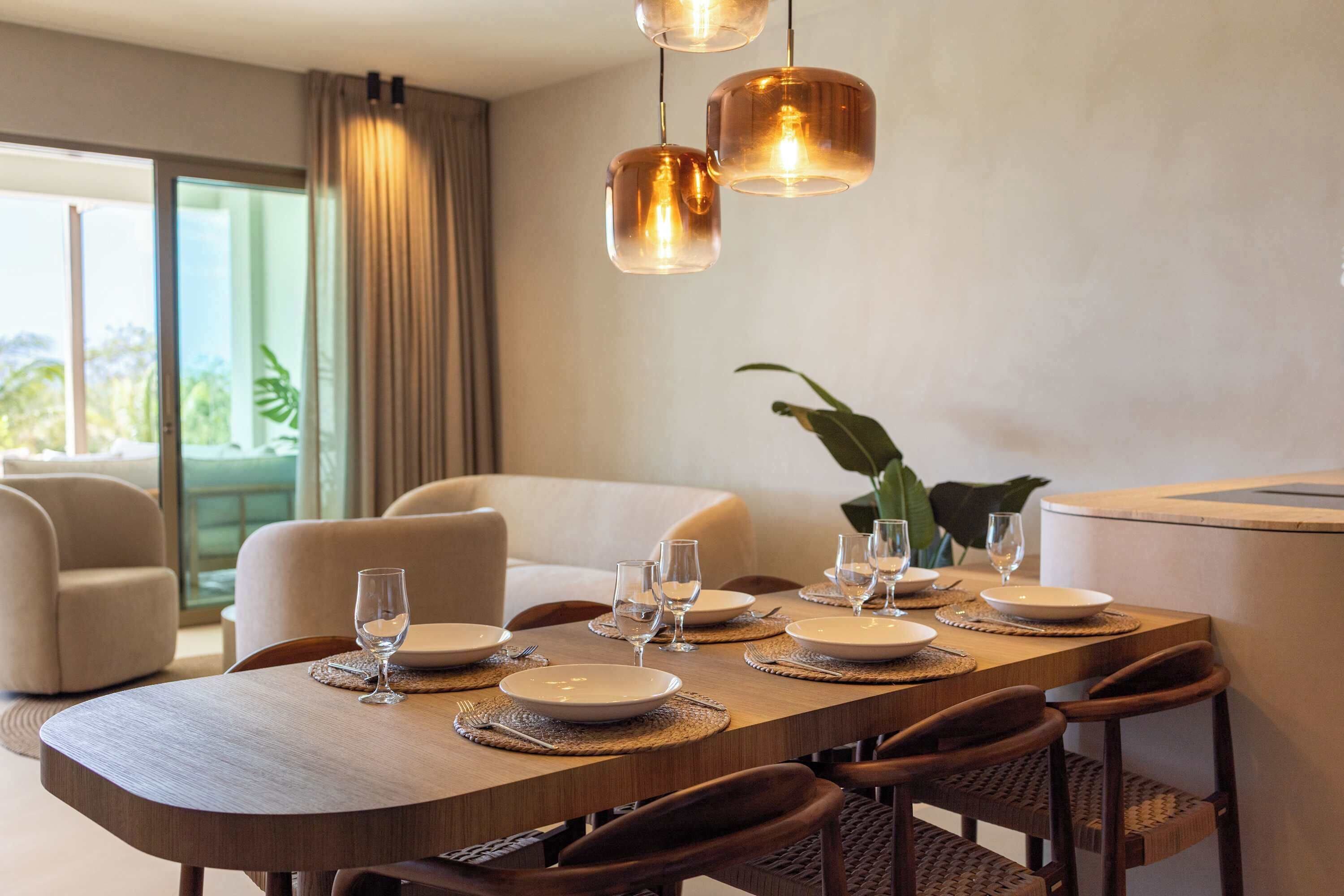 A dining area with a wooden table set for six, surrounded by upholstered chairs.