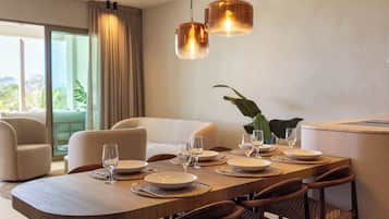 Uma sala de jantar com mesa de madeira posta para seis pessoas, cercada por cadeiras estofadas.