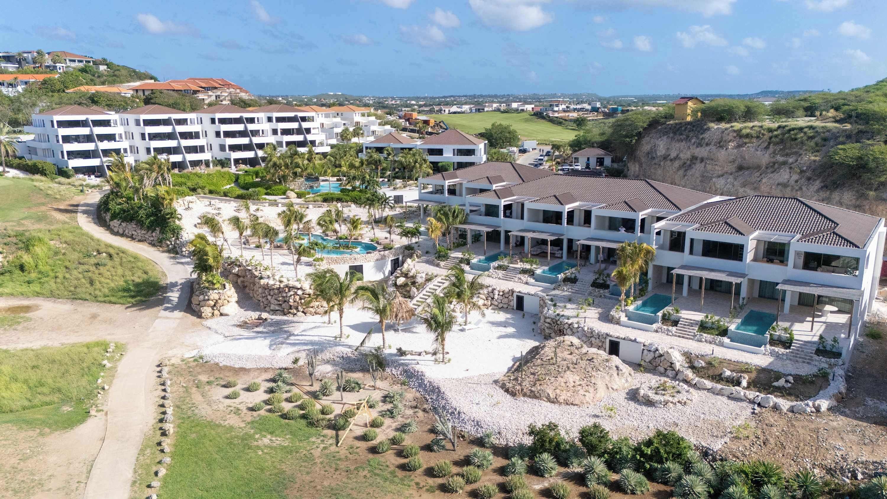 Um resort com vários edifícios, área de piscina e vista para a paisagem ao redor.