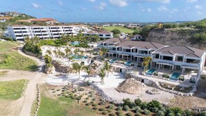 Ein Resort mit mehreren Gebäuden, einem Poolbereich und Blick auf die umliegende Landschaft.