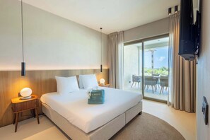 Quarto de hotel moderno com uma cama grande, duas mesas de cabeceira, uma TV de tela plana e vista para o exterior.